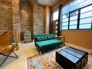 a living room with a green couch and a chair at Exposed Brick Flat Finsbury Park in London