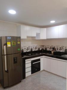 a kitchen with a stainless steel refrigerator and white cabinets at Casa en Santa Marta in Santa Marta