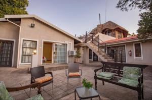 een patio met stoelen en een tafel en een huis bij The Catwalk Lodge in Pretoria