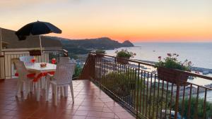 een tafel en stoelen op een balkon met uitzicht op de oceaan bij Perla d'Orlando in Capo dʼOrlando
