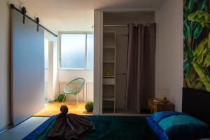 1 dormitorio con cama, ventana y espejo en Sibèl Appart, en Fort-de-France