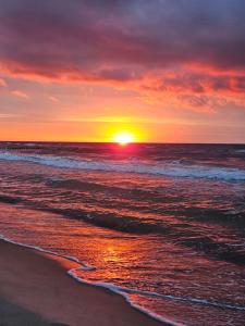 a sunset on a beach with the ocean at OW Plaża Klub domki in Dziwnów