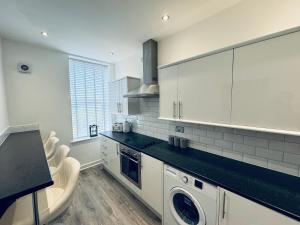 uma cozinha com armários brancos e uma máquina de lavar roupa em Spanish City View, Stylish Sea Front Apartment Free Onsite Parking em Whitley Bay