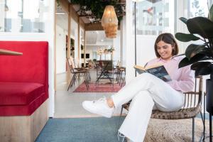 una mujer sentada en una silla leyendo un libro en Résidence Kley Angers Centre en Angers