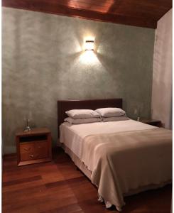 ein Schlafzimmer mit einem Bett und einer Lampe an der Wand in der Unterkunft Casa na represa in Vargem