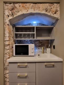 a kitchen with a microwave and a stone wall at Studio Flat With a View in Krakow