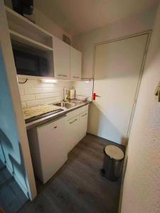 a small kitchen with white cabinets and a sink at T2 - au coeur de la roche in La Roche-sur-Yon