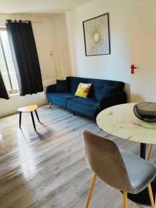 ein Wohnzimmer mit einem blauen Sofa und einem Tisch in der Unterkunft T2 - au coeur de la roche in La Roche-sur-Yon