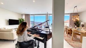 豐沙爾的住宿－Villa Obra-Prima by LovelyStay，女人在客厅弹钢琴