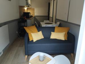 appartement cosy hyper centre de Cauterets في كوتيريه: غرفة معيشة مع أريكة زرقاء ووسائد صفراء