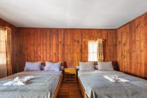 two beds in a room with wooden walls at Sawarna Little Hula Hula in Wangun