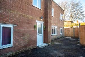 a brick building with a white door and a fence at Modern One Bed Flat Lowestoft in Lowestoft