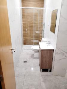 a bathroom with a toilet and a glass shower at Penedo Grande suítes T2 dúplex in São Bartolomeu de Messines