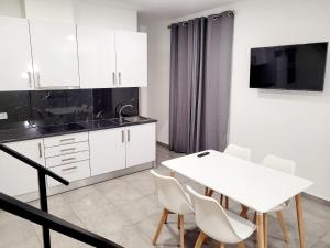 a kitchen with white cabinets and a white table and chairs at Penedo Grande suítes T2 dúplex in São Bartolomeu de Messines