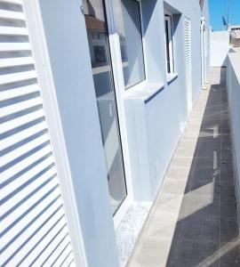 a white building with glass windows and a sidewalk at Penedo Grande suítes T2 dúplex in São Bartolomeu de Messines +6 photos