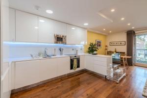 a kitchen with white cabinets and a hardwood floor at Beautiful Canal-side Flat in Hackney in London