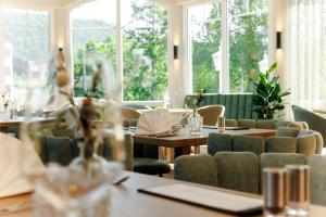 un comedor con mesas, sillas y ventanas en Wellnesshotel Sanct Bernhard en Bad Ditzenbach