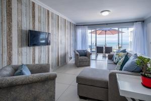 a living room with a couch and a tv at De Bakke Terrace 26 in Mossel Bay