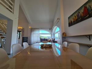 a dining room with a large table and white chairs at Cento Blu Villa in Gouvia