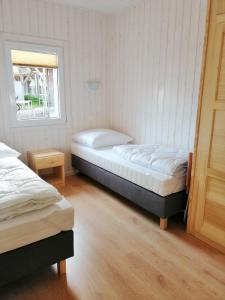 two twin beds in a room with a window at OW Plaża Klub domki in Dziwnów