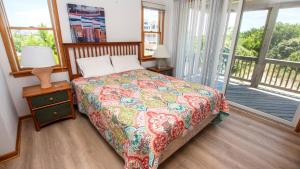 a bedroom with a bed with a colorful bedspread and a balcony at Oceanside, 5 BRs, Community Amenities, Keyless Entry, VOH2, Corolla Del Mar in Corolla