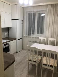eine Küche mit weißen Schränken sowie einem Tisch und Stühlen in der Unterkunft Lux апартаменты ЖК 7я in Astana