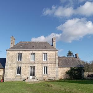 una gran casa de ladrillo con dos chimeneas en la parte superior en Cottage chaleureux à 25 mn de la côte de granit rose en Bégard