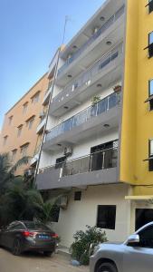 un gran edificio de apartamentos con coches aparcados frente a él en LUXE Appartement, en Dakar