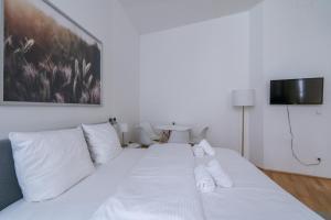 a white bed with white pillows in a room at Cosy Apartment Naschmarkt I new furnished in Vienna