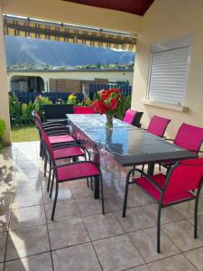 a patio with a table and pink chairs at Ti kaz anturium in La Possession