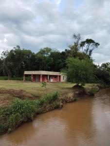 un edificio rojo junto a un río junto a un río en Casa de arroyo en Leandro N. Alem