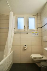 a bathroom with a toilet and a tub and two windows at Swiss Stay - 2 Bedroom Apartment close to ETH Zurich in Zürich