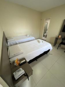 a bedroom with a large bed and a table with a phone at SD Plaza Hotel in Sobral