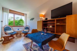 un soggiorno con tavolo, sedie e TV di Appartamento Indaco Armonya a Merano