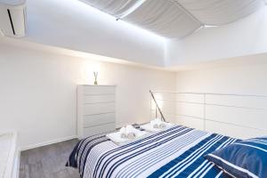 Dormitorio blanco con cama de rayas azul y blanco en Exclusive Loft Crocetta - Free Private Parking & Wi-Fi - 5 min To Metro Nizza en Turín