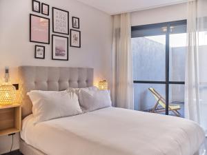 una camera da letto con un grande letto bianco e una finestra di TheCasaEdition Gauthier Residency City Center a Casablanca