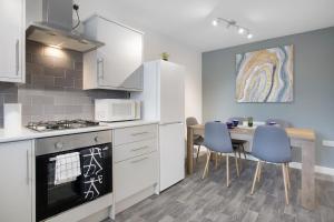 uma cozinha com uma mesa e um frigorífico branco em Charming 3 Bedroom House in Hartlepool, Sleeps 5 em Hartlepool
