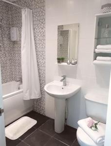 a white bathroom with a sink and a toilet at Beside the Seaside Tynemouth in Cullercoats