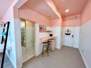 a home office with pink walls and a desk and stool at Peninsula Bed & Cocktails in St. Petersburg