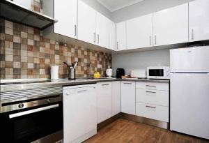 a kitchen with white cabinets and white appliances at Oeiras 4 in Oeiras