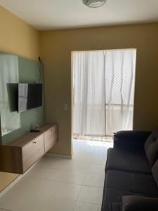 ein Wohnzimmer mit einem TV und einem Fenster in der Unterkunft Belíssimo apto proximo a praia do aracagy in São José de Ribamar