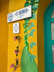 un panneau sur un mur jaune avec des fleurs et des plantes dans l'établissement El Barrio Hostal, à Carthagène des Indes