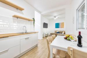 una cocina con armarios blancos y una mesa con un bol de fruta en Renovated Apartment on Salinetas Beach. en Salinetas