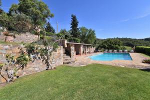 a backyard with a swimming pool and a stone wall at Casanovina in Castellina in Chianti