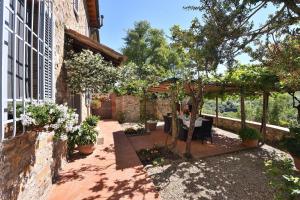 a garden with a pergola and a table and trees at Casanovina in Castellina in Chianti