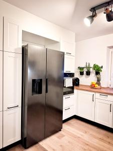 un frigorifero in acciaio inossidabile in una cucina con mobili bianchi di Schönes modernes Einfamilienhaus für 1 bis 6 Personen a Rimpar