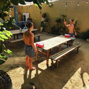two men standing in front of a picnic table at La Palmera Hostel in Puerto Escondido