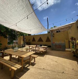 a group of picnic tables under a white umbrella at La Palmera Hostel in Puerto Escondido