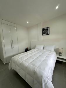 a white bedroom with a large bed and a cabinet at Cantares Adults Only in Cancún