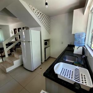 una cocina con nevera, fregadero y escaleras en Residencial Rota do Sol Bombinhas Centro 100 metros da praia, en Bombinhas